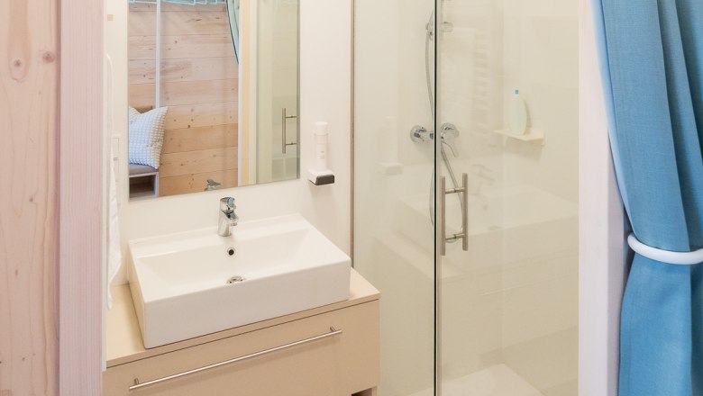 Badezimmer, © freilich / IsaBella Fritsche Modernes Badezimmer mit Waschbecken, Spiegel, Dusche und blauen Vorhängen.