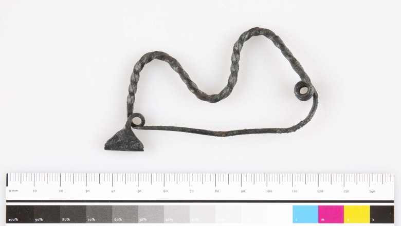 Fibel (Gewandspange) aus einem hallstattzeitlichen Grubenhaus, © Landessammlungen Niederösterreich / UF-19842.1 Metallobjekt mit verdrehtem Draht und Maßstab.