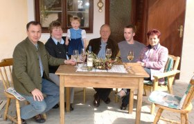 Familienbetrieb, © Familie Arocker Eine Familie sitzt an einem Holztisch im Freien und trinkt Wein.