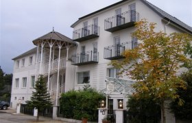 Eingang, © Villa Nina Ein mehrstöckiges Gebäude mit Balkonen und einem Eingang mit Säulen.