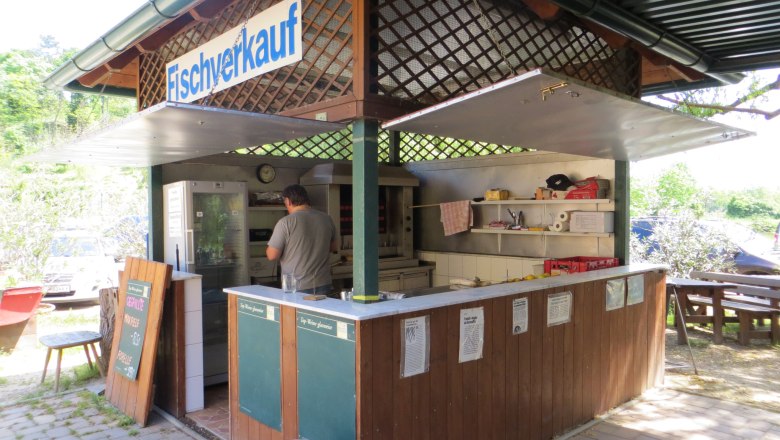 Fischverkauf, © Urani Ein kleiner Fischverkaufsstand im Freien mit einem Mann, der im Inneren arbeitet.