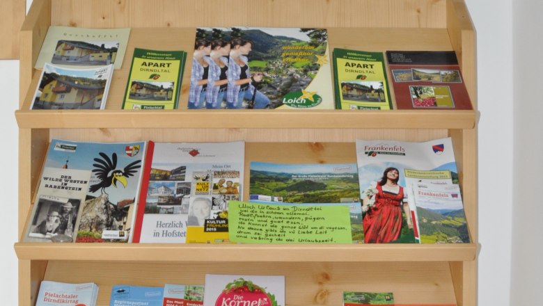 Apartment Dirndltal, © Familie Krückel Ein Regal mit Broschüren und einem Schild mit 'Herzlich Willkommen Familie Krückel'.