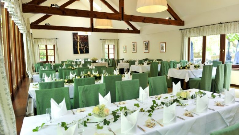 Klostergasthaus Thallern, © Klostergasthaus Thallern Innenansicht eines festlich gedeckten Gasthauses mit grünen Stühlen und Holzbalken.