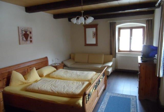 Doppelzimmer Ried Hauersteig, © Familie Denk Gemütliches Doppelzimmer mit Holzbett, Sofa und Fenster.