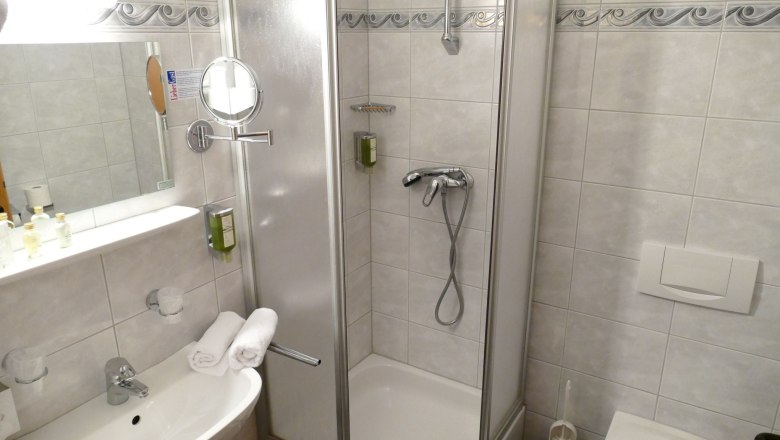 Pool bei Nacht, © Besta Betriebs GmbH Badezimmer mit Dusche, Waschbecken und Spiegel.