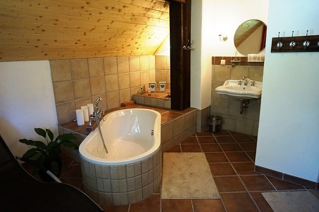 Rustikales Wellnessbad, Bio-Bauerhof Prannleithen, © Schroll Rustikales Badezimmer mit Badewanne, Waschbecken und Holzdecke.