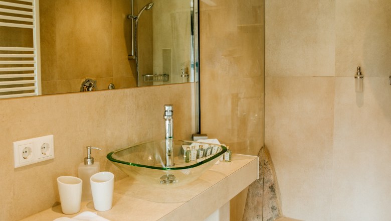 villa_schonthal-17_3, © Julius Hirtzberger Modernes Badezimmer mit Glaswaschbecken und begehbarer Dusche.