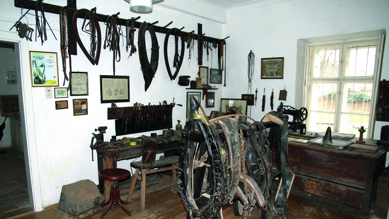 Heimatmuseum Wilfersdorf, © J. Schimmer Ein Raum in einem Heimatmuseum mit alten Werkzeugen und Pferdegeschirr an den Wänden.