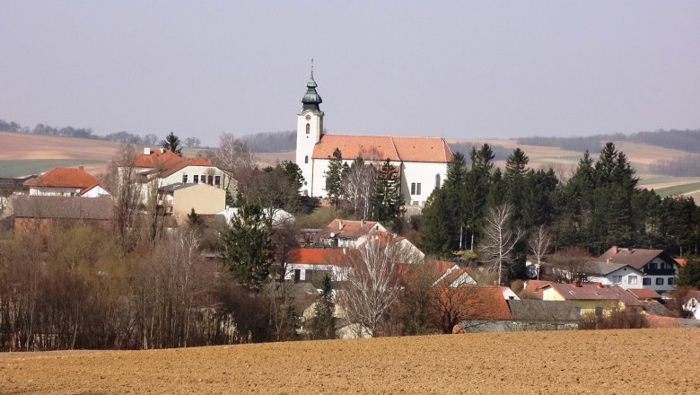 Gnadendorf, © Gemeinde Gnadendorf Blick auf das Dorf Gnadendorf mit Kirche und umliegenden Häusern in ländlicher Landschaft.