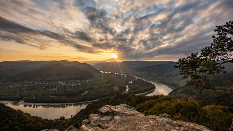 Ausblick von der Kanzel in Dürnstein, © Robert Herbst Sonnenuntergang über der Donau in Dürnstein, mit Blick auf Fluss und Hügel.