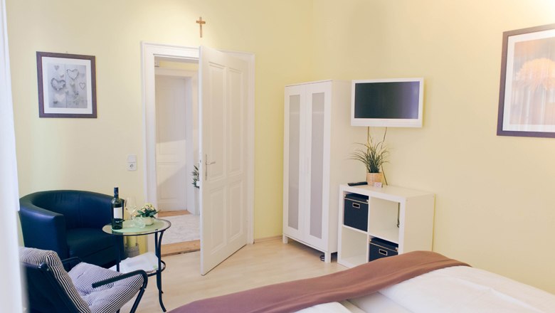 Appartment & Gästezimmer "Vino Verde", © Fam. Willmann Helles Gästezimmer mit Bett, Sessel, Tisch, Schrank und Fernseher.