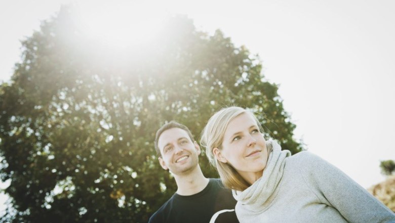 Maria und Josef Maier, © Bioweingut Geyerhof Ein Mann und eine Frau stehen im Freien vor einem Baum, die Sonne scheint durch die Blätter.