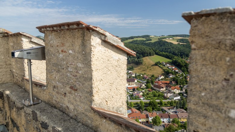 Blickplatz Feuerturm Burgruine, © Wiener Alpen, Foto: Franz Zwickl Aussicht von einer Burgruine auf eine Stadt und grüne Hügel.