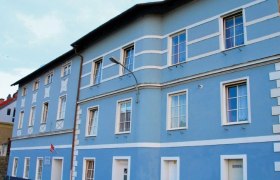 Pension Hausansicht, © Michael Krieger Blaue Fassade eines mehrstöckigen Gebäudes mit weißen Fensterrahmen und Türen.