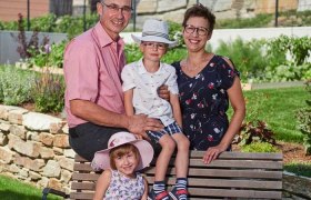 Familie Stradinger, © Familie Stradinger Eine Familie sitzt auf einer Bank im Garten, bestehend aus zwei Erwachsenen und zwei Kindern mit Hüten.