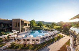 Außenpool des Vivea Hotel zur Quelle, © Vivea Gesundheitshotel Bad schönau zur Quelle Außenansicht des Vivea Gesundheitshotels Bad Schönau mit Pool und Sonnenschirmen.