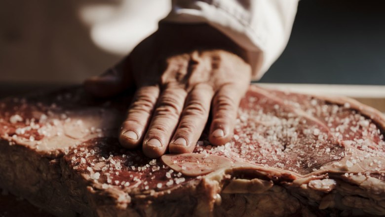 Ausgezeichnetes Handwerk trifft beste Fleischqualität, © Niederösterreich Werbung/Michael Reidinger Nahaufnahme einer Hand, die grobes Salz auf ein großes Stück rohes Fleisch streut.