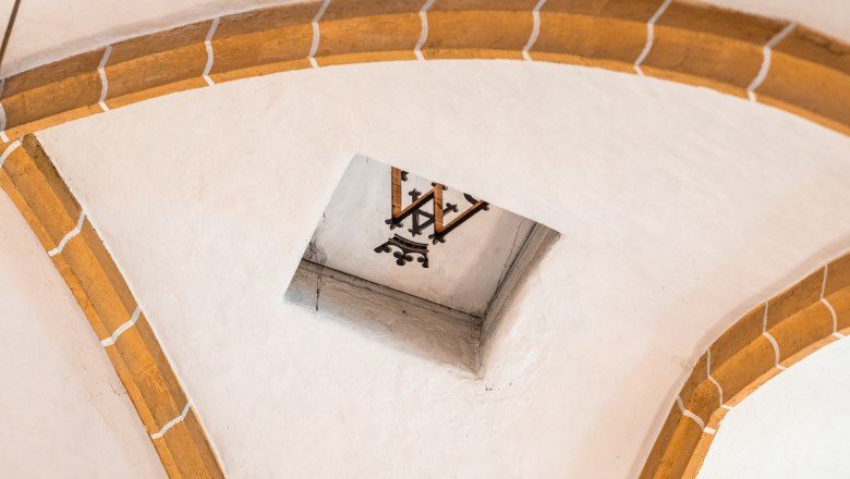 Innenansicht eines Gewölbes mit Ziegelbögen und einem dekorativen Element in der Mitte.