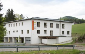 Ein weißes Gebäude mit der Aufschrift 'Brandtner' in ländlicher Umgebung.