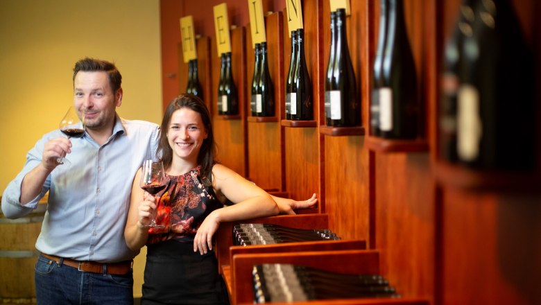 Zwei Personen in einem Weinkeller mit Weingl&auml;sern in der Hand.