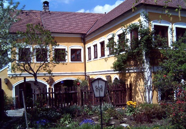 Gelbes Haus mit roten Dachziegeln und Garten im Vordergrund.