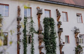 Fassade eines Gebäudes mit dekorativen Holzstrukturen und Pflanzen.