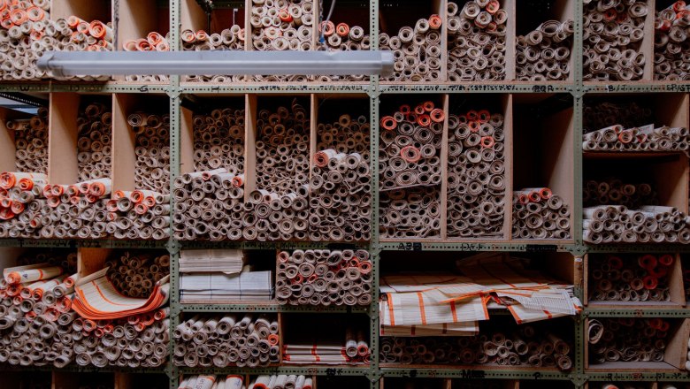 Regal mit vielen gerollten Papierdokumenten in F&auml;chern.