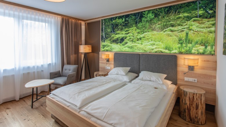 Hotel Sole Felsen Welt, © Sole Felsen Welt - Peter Baier Modernes Hotelzimmer mit Doppelbett, Naturbild an der Wand, Sessel, Tisch und Stehlampe.
