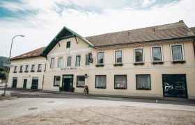 Ein traditionelles Gasthaus mit gelber Fassade und gr&uuml;nen Fensterl&auml;den, beschriftet mit 'Gasthof zur Wachau'.