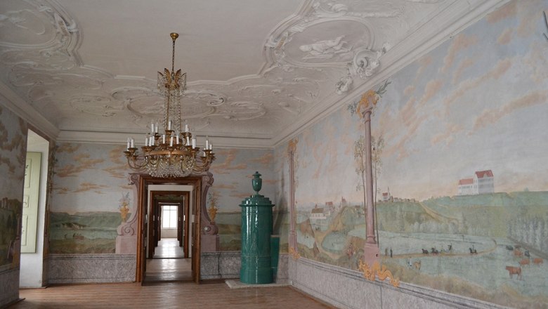 Eleganter Raum im Schloss Stetteldorf mit Wandmalereien und einem Kronleuchter.
