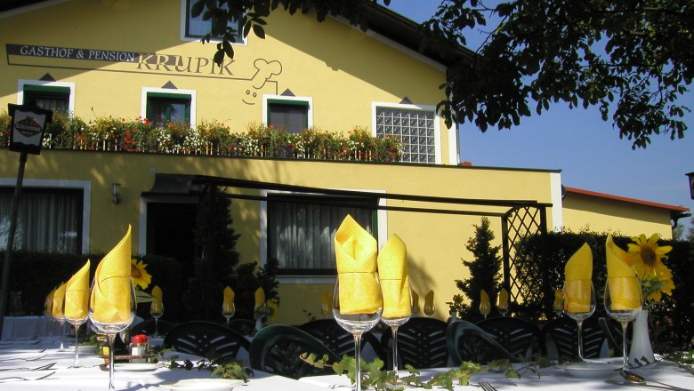 Gasthof Krupik, © Renate Krupik Außenansicht des Gasthofs Krupik mit gedecktem Tisch im Vordergrund.