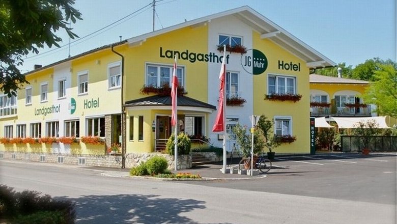 Gelbes Landgasthof-Hotel mit Blumenkästen und österreichischen Flaggen.