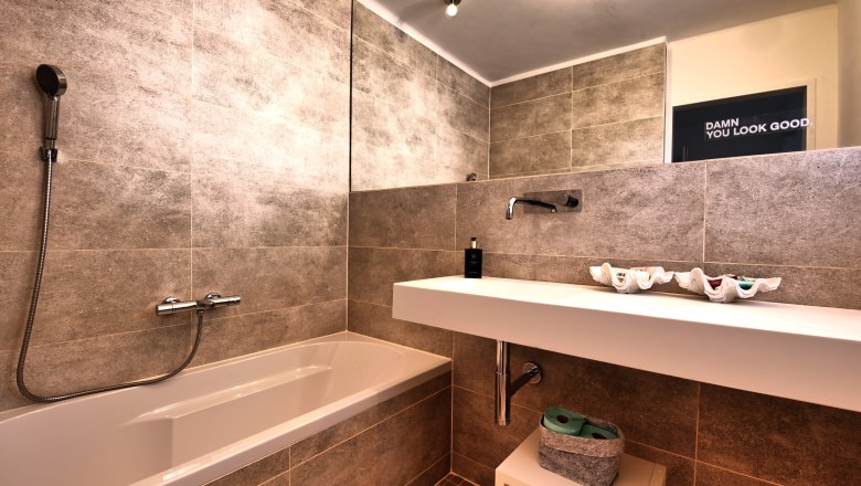 Modernes Badezimmer mit Badewanne, Waschbecken und gro&szlig;em Spiegel.