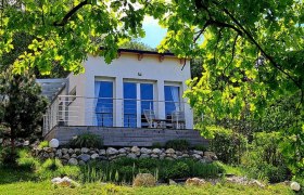 Ein modernes Chalet mit großer Fensterfront, umgeben von grüner Natur und Bäumen.