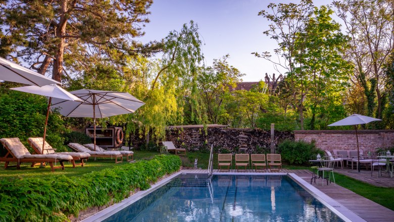 Garten mit Pool, Liegestühlen und Sonnenschirmen im Hotel Landhaus Moserhof.