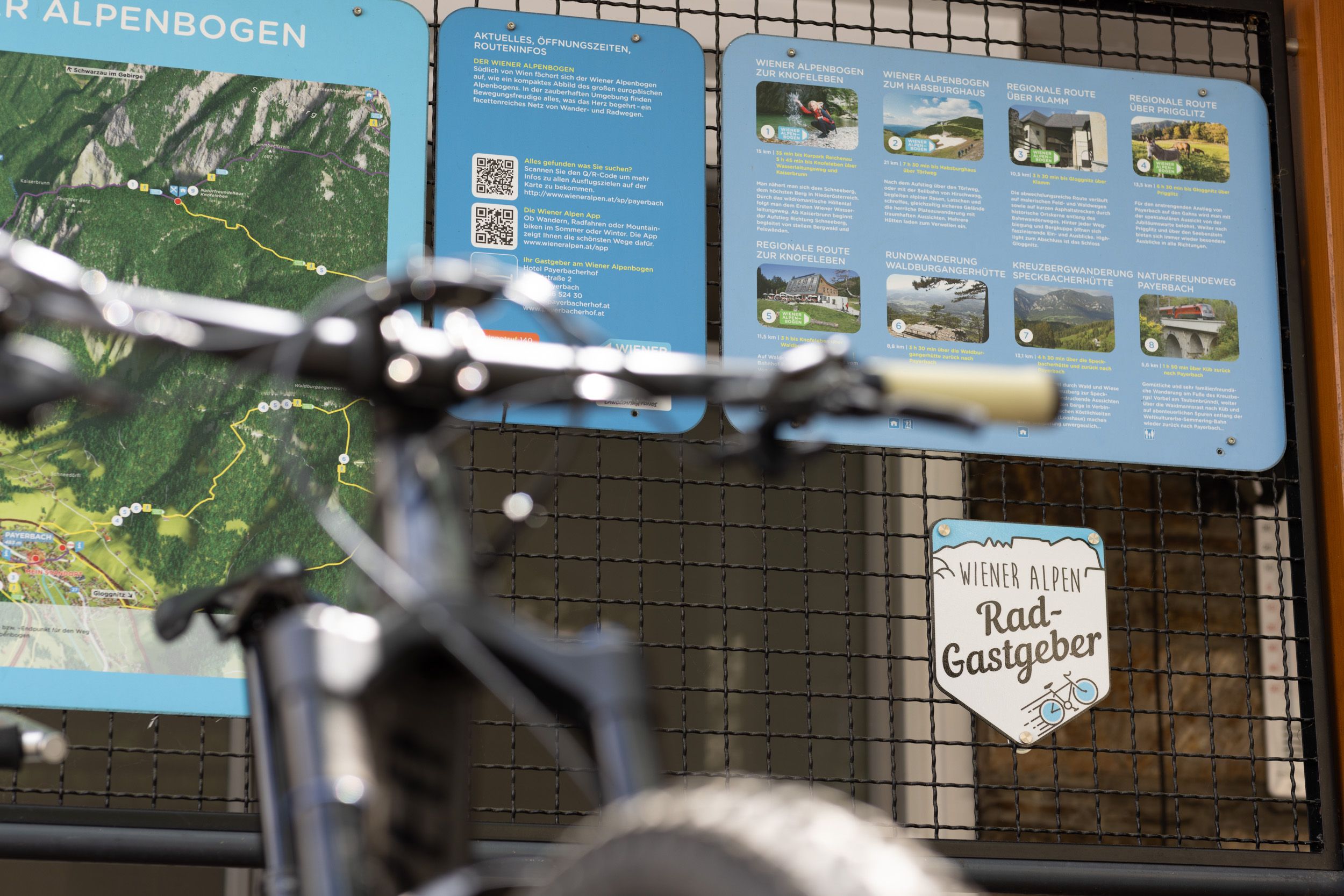 Ein Fahrrad steht vor einer Infotafel mit Wander- und Radwegen in den Wiener Alpen.