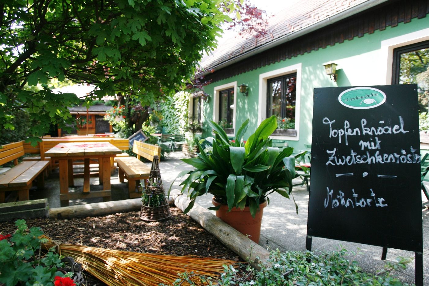 Gemütlicher Gastgarten mit Holzbänken und Tafel im Wirtshaus Bonka, Wienerwald.