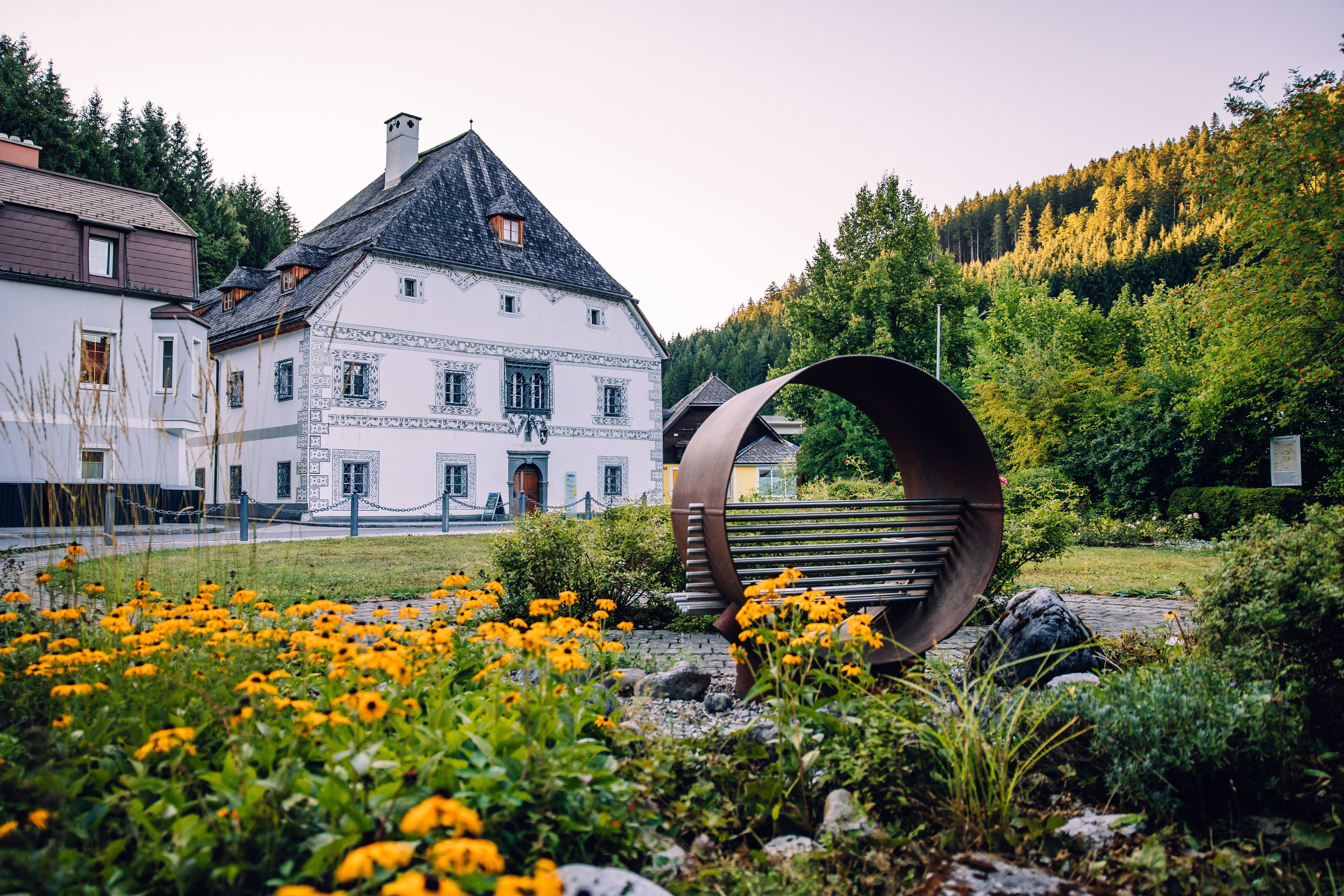 Amonhaus in Lunz am See, mit Hörsessel im Vordergrund und Blumenbeet vor dem historischen Gebäude.