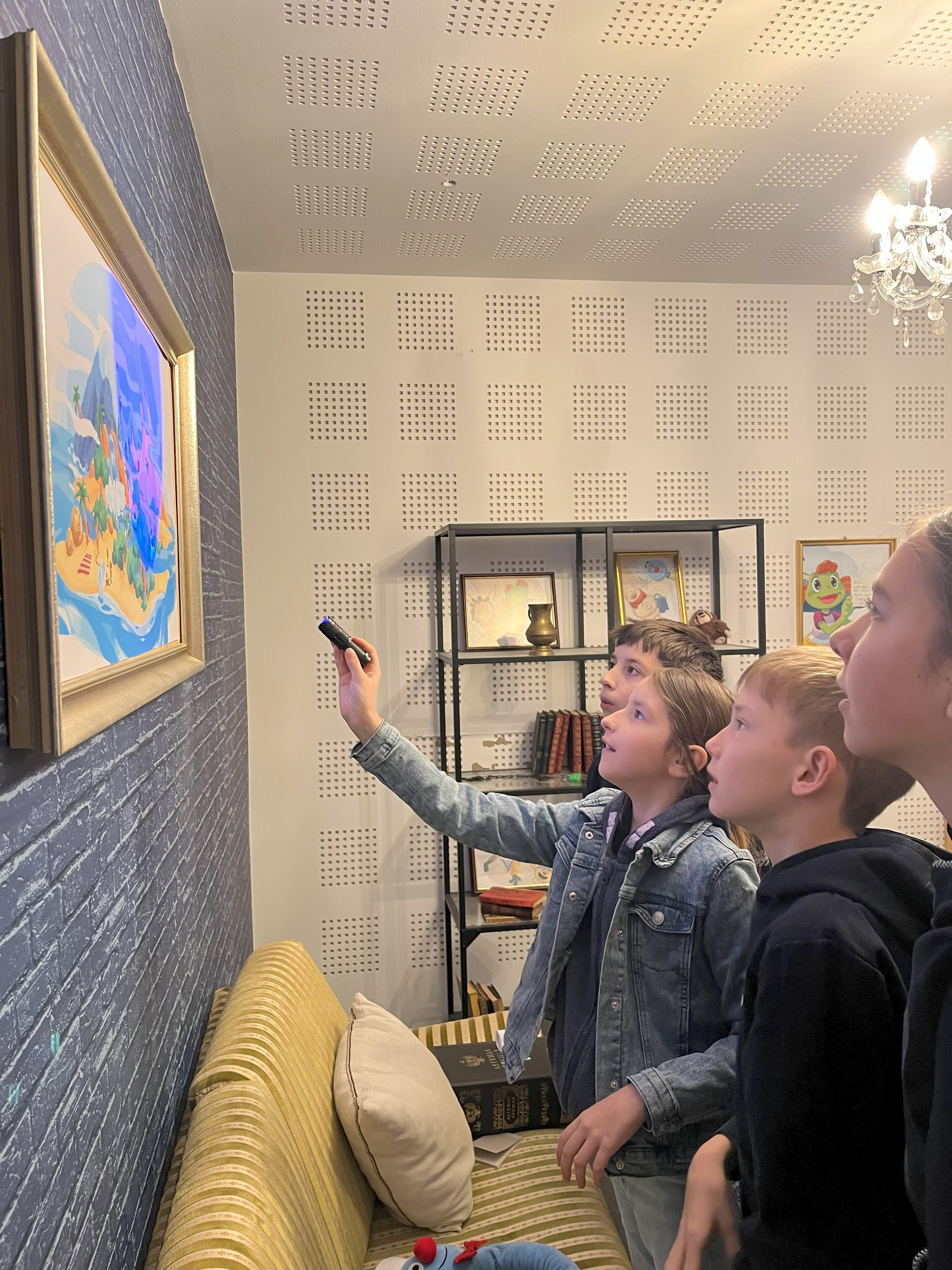 Kinder beleuchten ein Bild mit Blaulicht um ein Rätsel zu entschlüsseln 