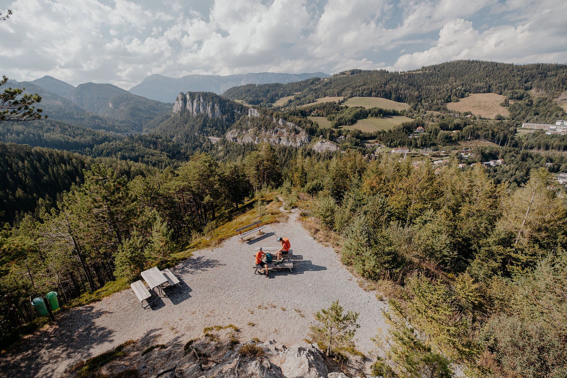 Zwei Wanderer machen Pause auf einer Bank vor dem 20 Schilling Blick