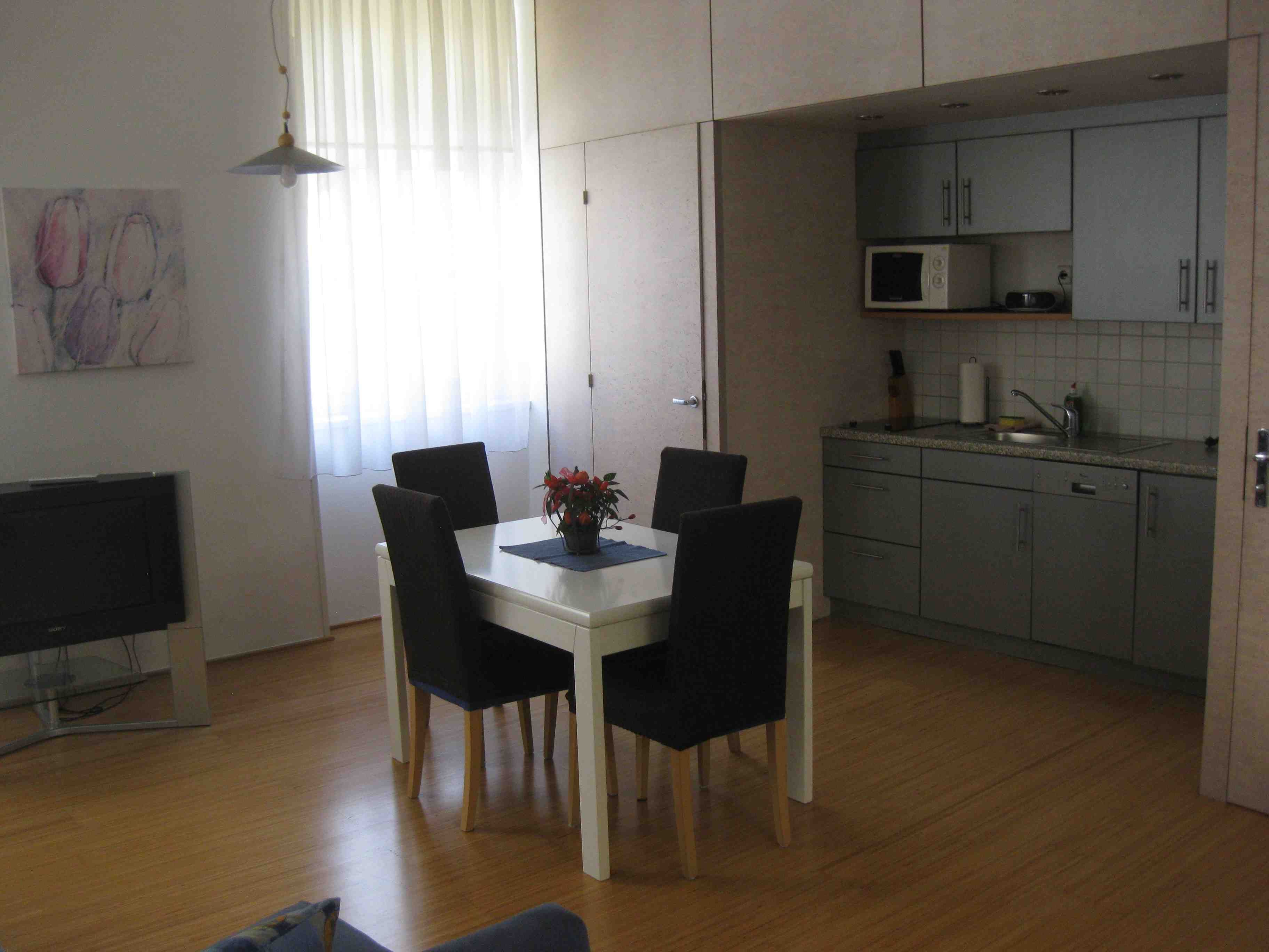 Graue Küchenzeile mit Esstisch und blauen Stühlen.