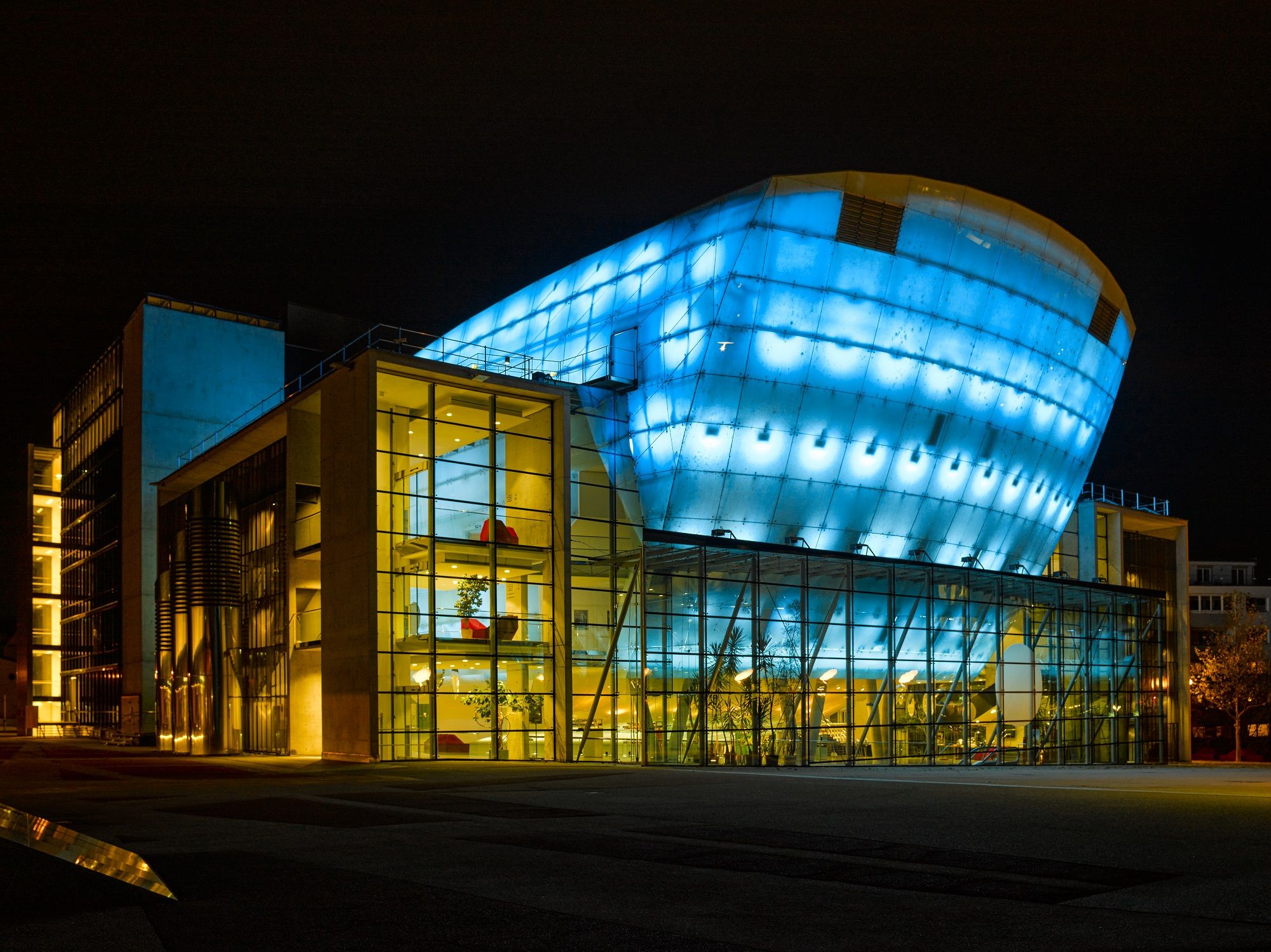 Festspielhaus St. Pölten bei Nacht, beleuchtet in Blau und Gelb.