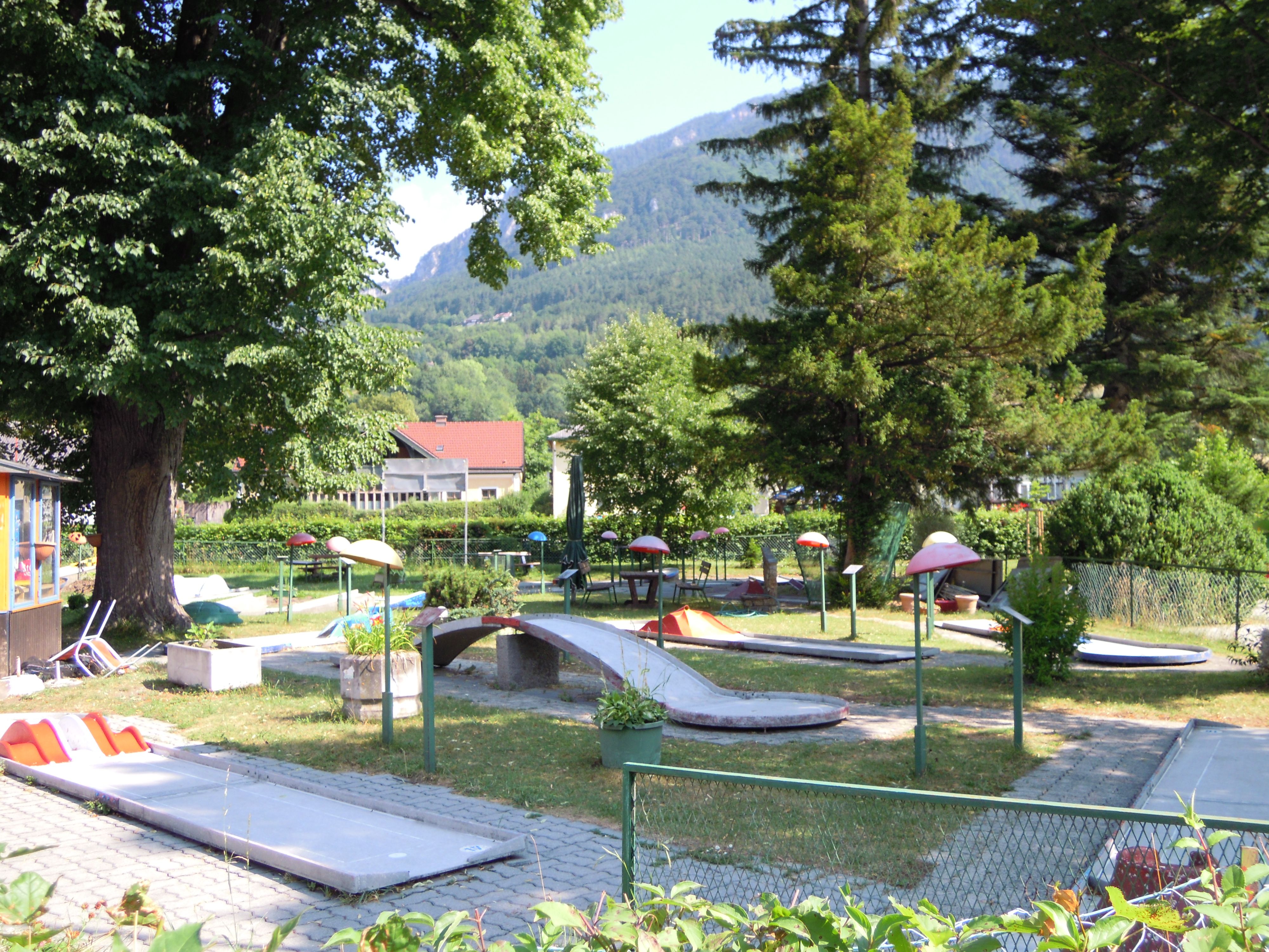 Minigolfplatz in Payerbach mit Bäumen und Bergen im Hintergrund.