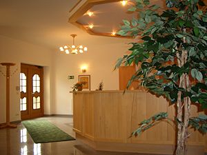 Empfangsbereich eines Gasthofs mit Holztresen und Pflanze.