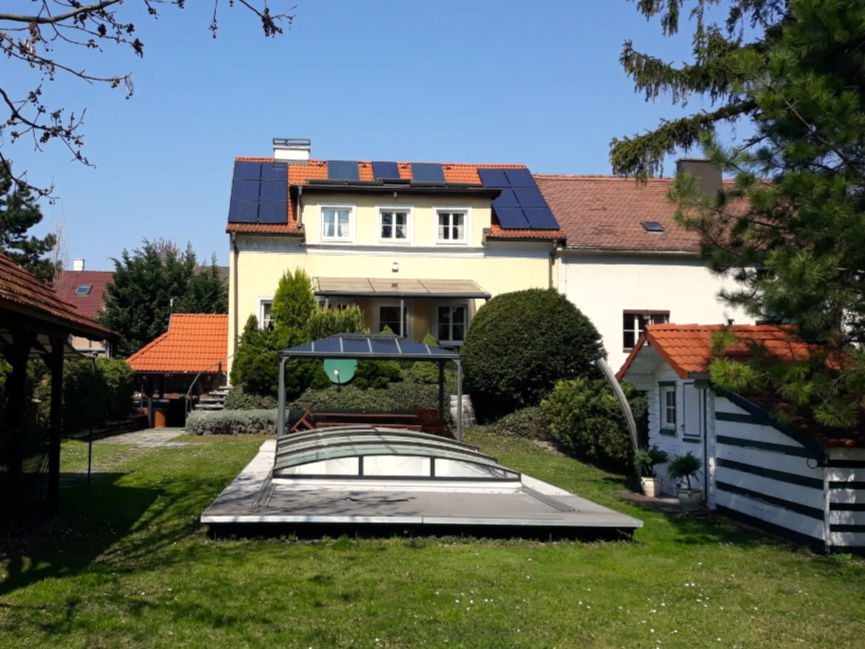 Ein Haus mit Solarpanelen und einem überdachten Pool im Garten.