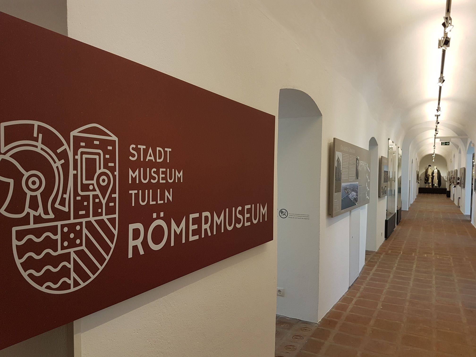 Innenansicht des Stadtmuseums Tulln Römermuseum mit einem langen Flur und Ausstellungsstücken an den Wänden.