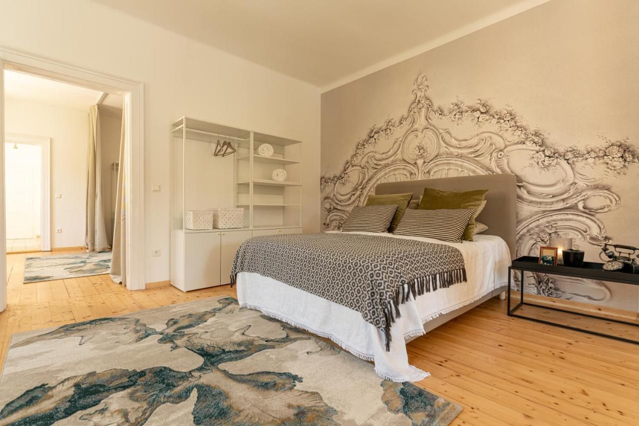 Ein stilvoll eingerichtetes Schlafzimmer mit einem großen Bett, dekorativen Kissen, einem Teppich und einer kunstvollen Wandgestaltung.