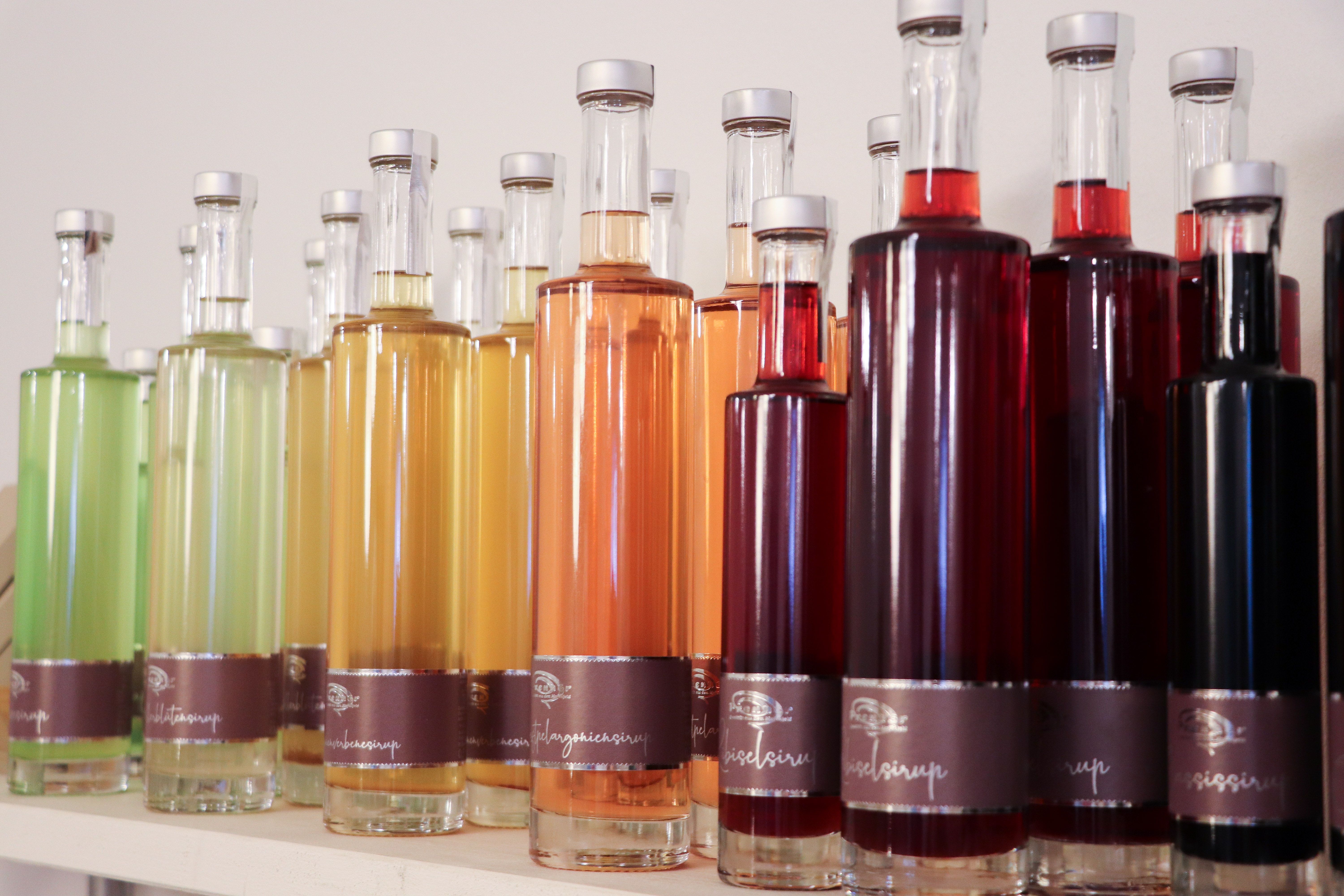 Verschiedene bunte Sirupflaschen in einer Reihe auf einem Regal.