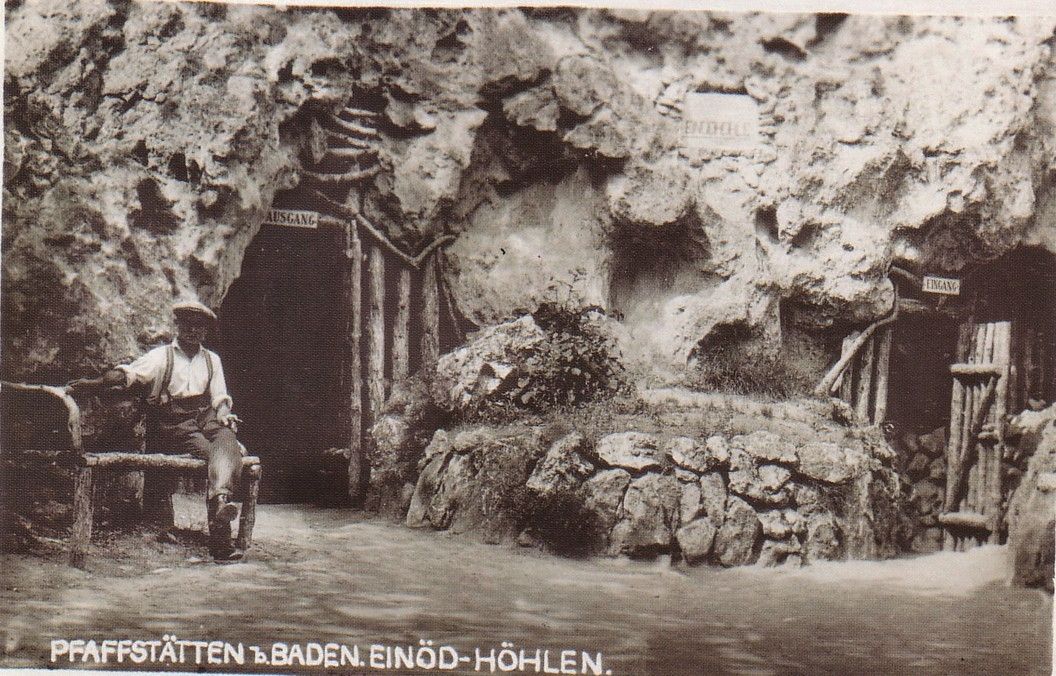 Historisches Foto der Einödhöhle in Pfaffstätten, Baden, mit einem Mann auf einer Bank vor dem Höhleneingang.