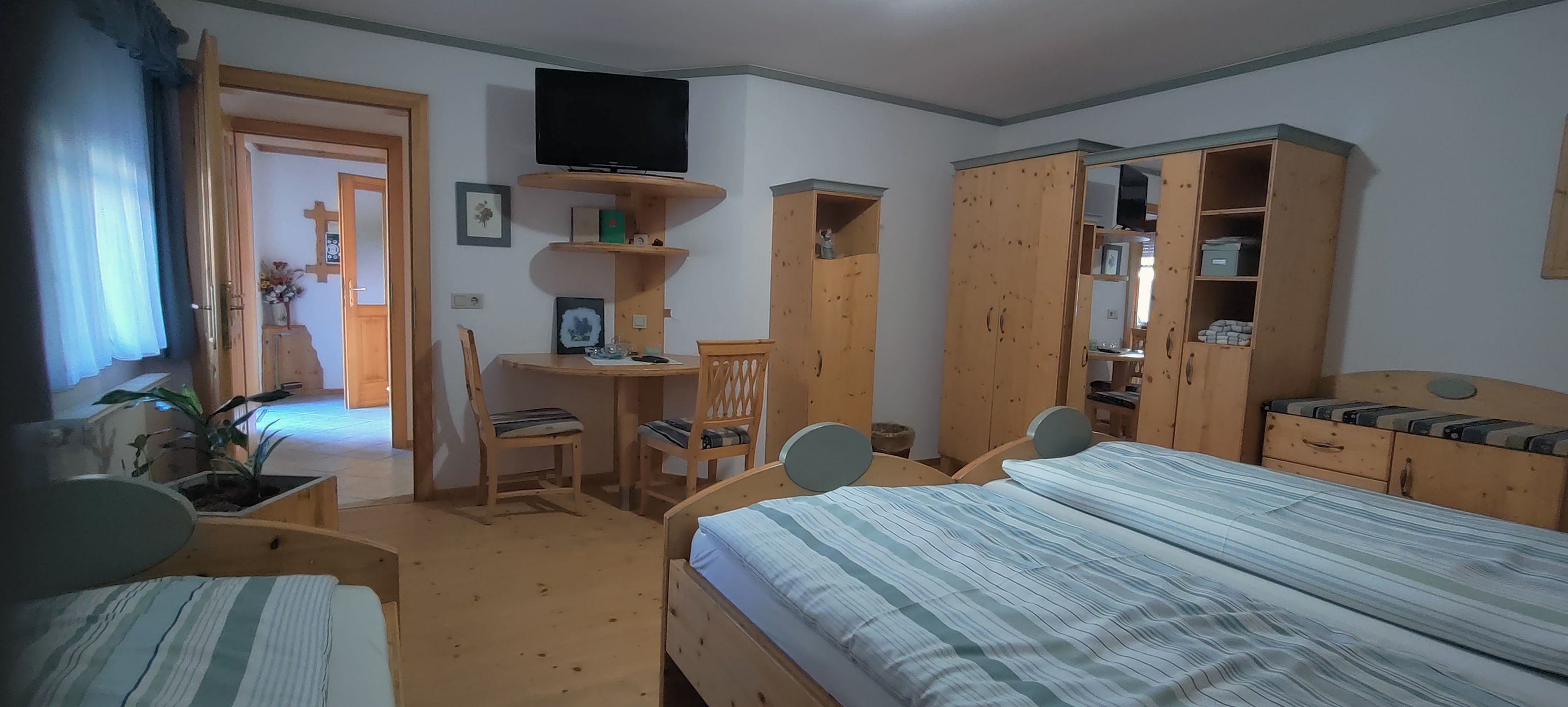 Gemütliches Schlafzimmer mit Holzmöbeln, Doppelbett, Schreibtisch und Fernseher.